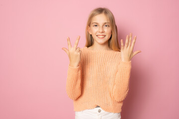 Little smiling girl counting eight standing isolated over pink background.