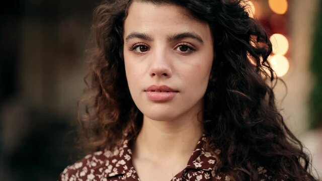 Close up fashion street stile portrait of pretty girl in fall casual outfit. Beautiful brunette woman with curly hair posing outdoor.