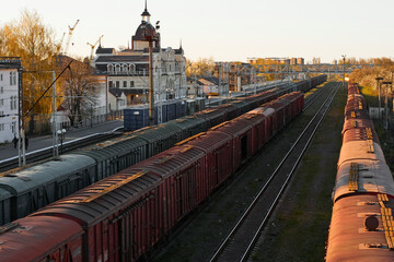 Lutsk, Ukraine - May 26,2021: Roofs of cargo train with shipping container in depot. Freight train carriages at railway station. Classification or sort rail yard. Locomotive with goods wagon on rails