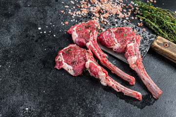 Raw uncooked lamb mutton meat chops steaks on a butcher cleaver. Black background. Top view. Copy space