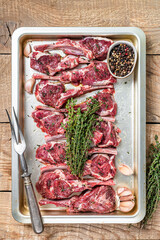 Raw uncooked lamb mutton meat chops steaks with thyme and garlic. Wooden background. Top view