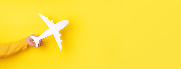 airplane symbol in hand over yellow background, panoramic layout