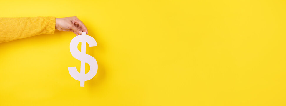 dollar symbol in hand over yellow background, panoramic layout
