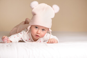 Cute adorable baby child with white and pink hat with cute bobbles. Happy baby looking at the camera. Close-up for xmas holiday and family concept.