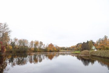 Fototapeta na wymiar Natural countryside autumn view of small lake with lovely yellow and orange trees around.
