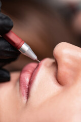 Young woman having permanent makeup on lips in beautician salon. Close up - obrazy, fototapety, plakaty