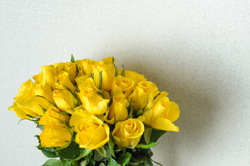 A bouquet of many delicate, yellow roses on a gray textured background.