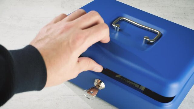 Man Hand puts a gun revolver pistol into the metal safe box. Lock Box with Key Closing. Passport, mobile and cash in safe with kay.