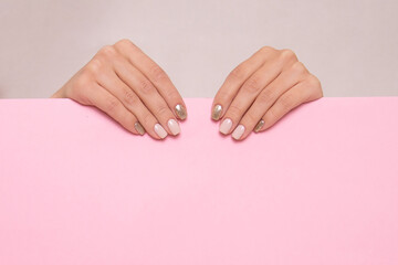 Beautiful female hands with beige manicure nails on pink background