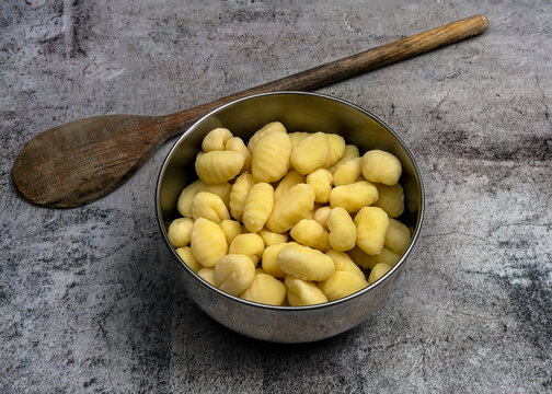 uncooked potato yoki in stainless steel bowl with wooden spoon