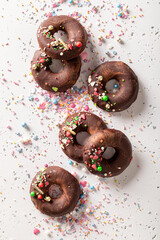 Dark brownie donuts with sprinkles and chocolate topping.
