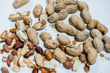 peeled peanuts and in their shell on a white surface.