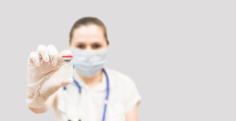 A female doctor holds an ampoule with a medicine or vaccine in her hand. Immunization and...