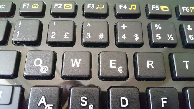 Close-up of a computer keyboard showing the Q and W keys, highlighting modern technology, typing, digital work, and everyday computing in an office or home setup.