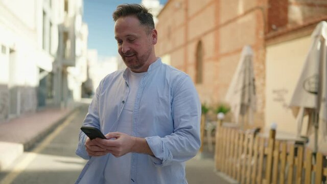 Young caucasian man smiling confident using smartphone at street