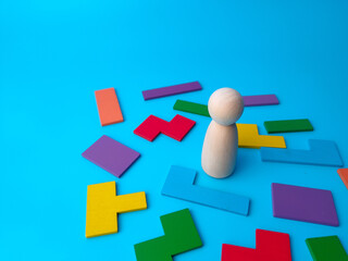 Wooden peg doll standing out from the colored wooden puzzle.Business concept idea.