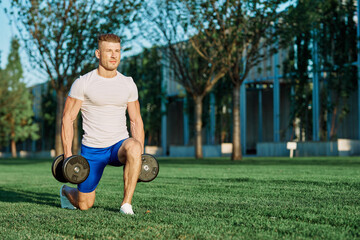 athletic man training with dumbbells in the morning Park