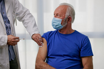 Elderly man receiving vaccine. Medical worker vaccinating senior patient against coronavirus,...