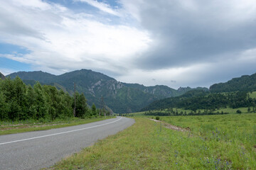 Fototapeta na wymiar asphalt road between mountain peaks. warm summer day