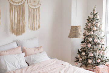 Light cozy bedroom decorated for celebrating Christmas. Eco style interior in white colors with...