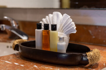 comptoir de salle de bain en pierre avec des produits et lotions présentés avec une serviette blanche pliée derrière