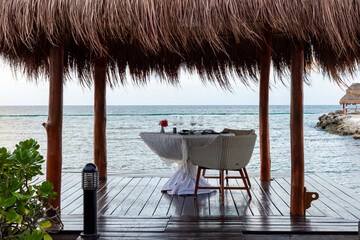 table préparée pour un souper romantique en bord de mer sous un toit de paille