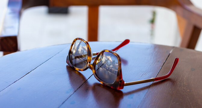 gros plan sur une paire de lunettes de soleil d&eacute;pos&eacute;e sur une table en plein jour  avec r&eacute;flection tropicale