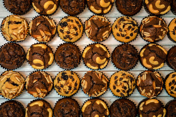 Top view of fresh homemade delicious vanila and chocolate muffins in paper cupcake holder isolated on wooden background.