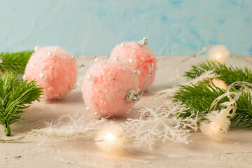 pink fluffy Christmas balls with beads snowflakes fir twigs and a Christmas tree garland on a gray surface