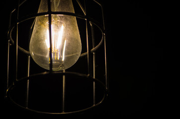Night photography of the light bulb with Metal Cage isolated on black background.