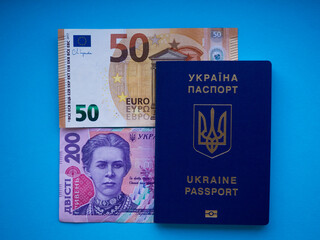 A set of European Union and Ukraine money with a face value of 50 euros and 200 hryvnia on blue. Background of the fifty euros, two hundred hryvnia banknotes and Ukraine passport with copy space. 