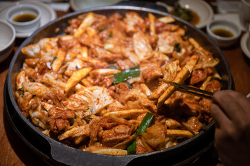 Hand using chopsticks to picking Dakgalbi barbeque chicken with vegetable mixed