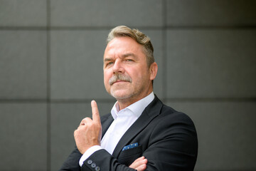Confident middle aged businessman pointing upwards with finger