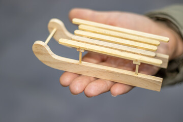 wooden sleigh in woman hand palm isolated.small little christmas home decoration, ready for painting.activities for kids,diy do it yourself school education lessons imagination, creativity