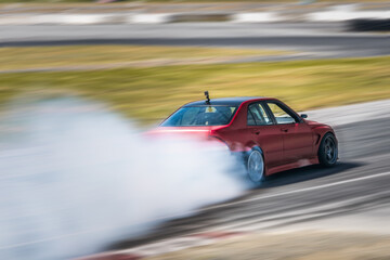 Red Drift Car / Race car drifting around corner very fast with lots of smoke from burning tires on...