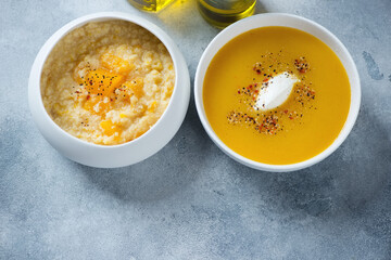 Millet porridge with pumpkin and pumpkin soup served in white bowls, high angle view on a light-blue stone background, horizontal shot