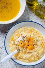 Plate of millet porridge with addition of pumpkin over beige granite background, elevated view, vertical shot, middle closeup