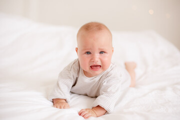 the baby is lying at home on the bed smiling