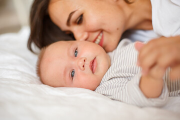 mom and baby are lying at home on the bed