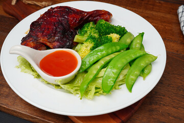 Grilled chicken marinated with spices and boiled fresh vegetables Broccoli, green peas, lettuce in a white plate