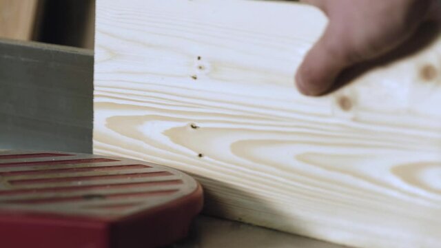carpenter work with wood joiner planer. male worker hands processing wood using machine tool. woodworker passes wooden board through traditional sawmill planer