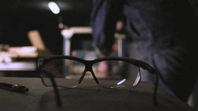 carpenter work with thickness planer in the background blurred background. carpenter's goggles lying on the workshop table. woodworking concept