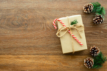 Beautiful Christmas background with gift box, decorate with pine branch and pine cone over wood background. Top view with copy space, flay lay.