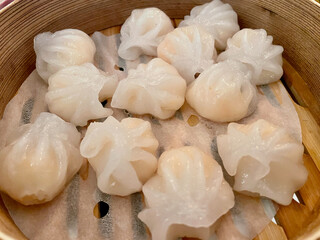Close up of fresh homemade Dim Sum, Chinese dumplings stuffed with shrimp and pork, in bamboo steamer.