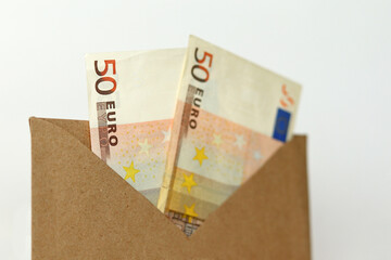 Paper euro banknotes in a brown paper envelope on a white background