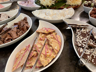 Assortment of handmade Swiss chocolate specialities in white bowls on black table. Closeup.