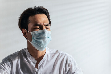 Male angry. Upset Asian young man wearing a face mask alone at a home office having problems or bad time financial. Trouble, stress, depression, illness, and Suffering in covid-19 coronavirus concept