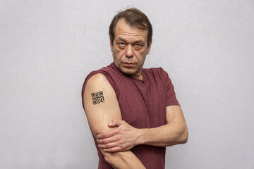 An elderly man with a QR code on his hand, confirmation of vaccination against the covid 19 coronavirus. Temporary tattoo. Scan the QR code using the mobile app. Evidence-based vaccination.