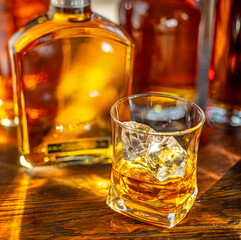 Whiskey decanter and glass of whiskey on the wooden bar counter close-up.