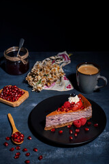 Raspberry Cheesecake with pomegranate seeds on black rustic background wit a cup of coffee 